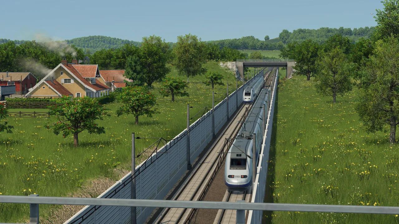 A white high-speed train running on double track through a grassy cutting near a farmhouse